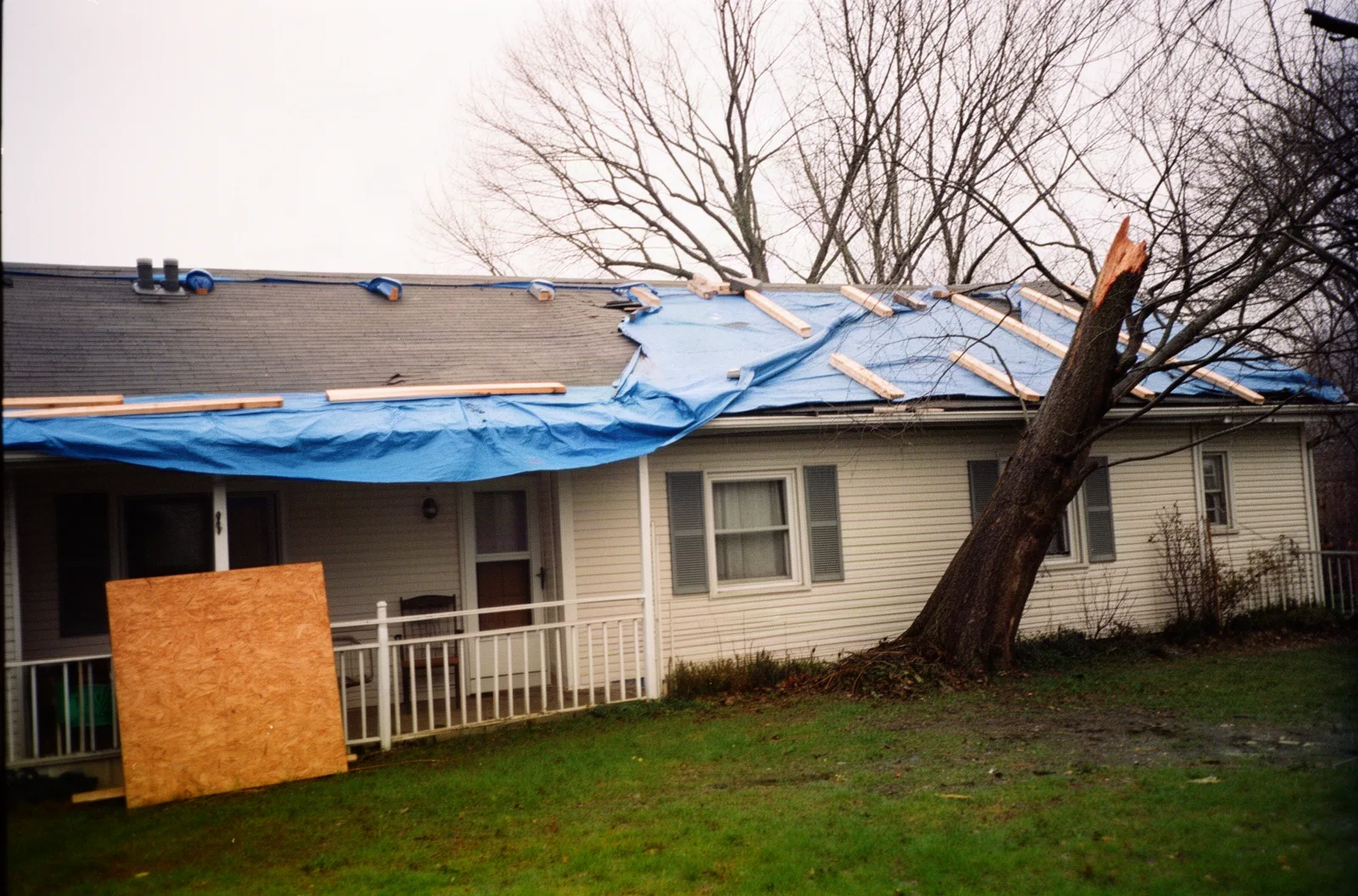 A blue tarp secured over a damaged roof section after a storm