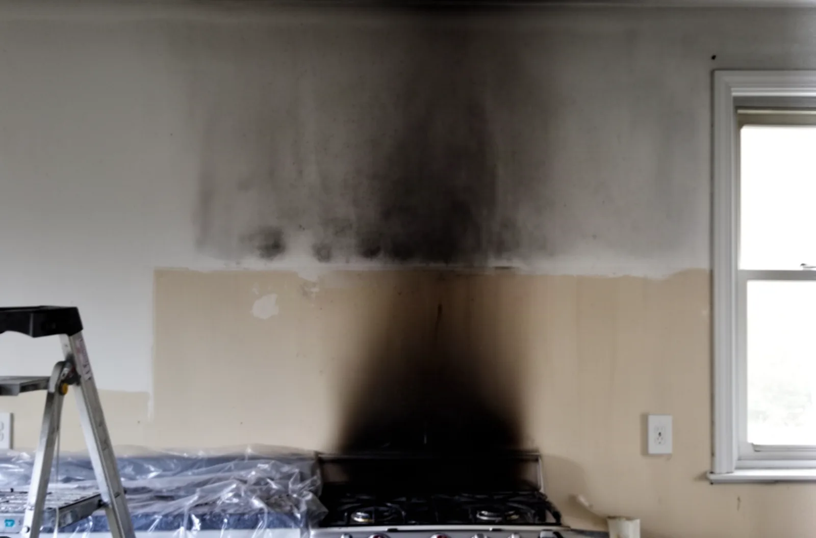 Soot staining above a kitchen stove alcove during cleanup