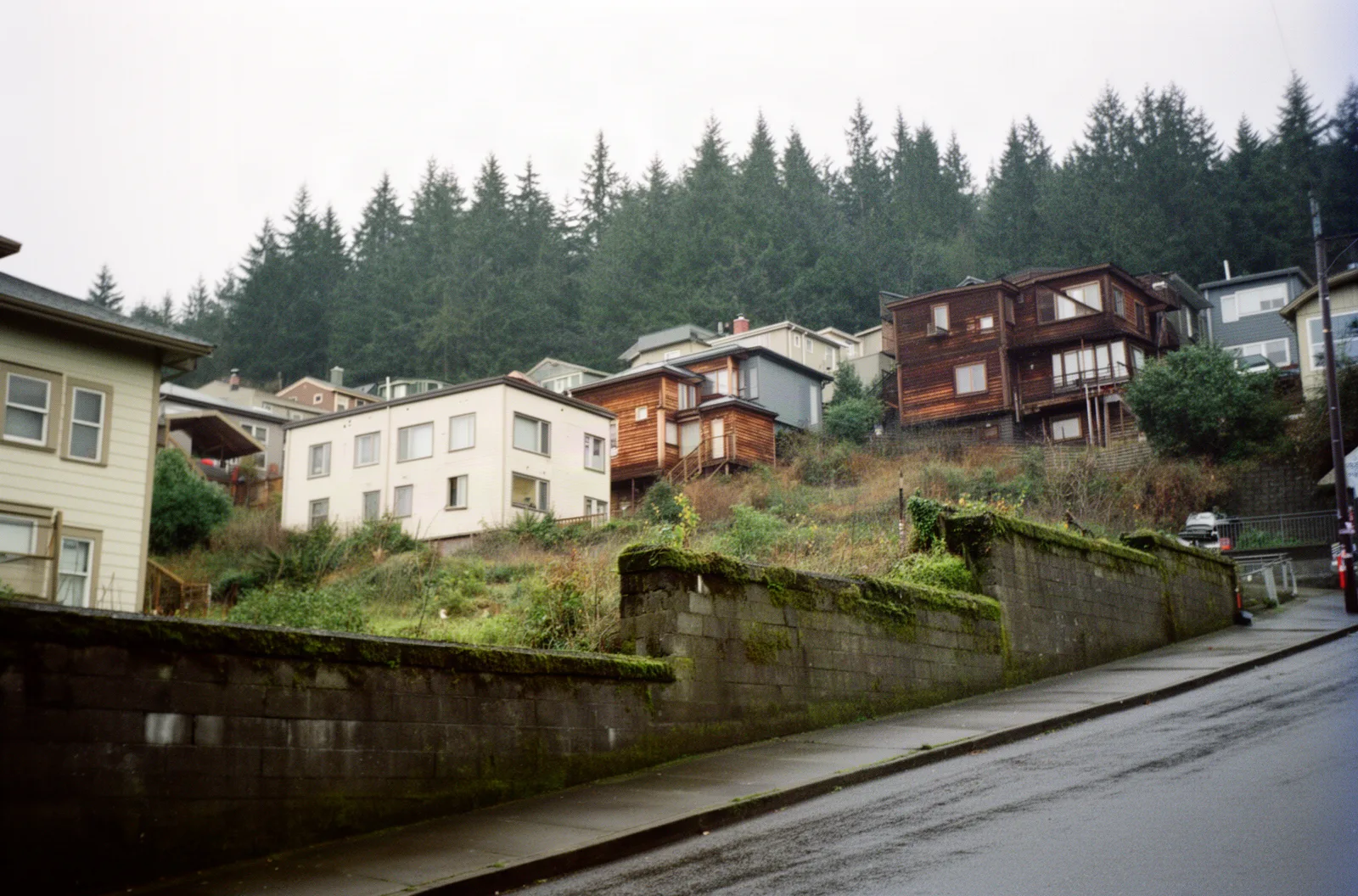 A sloping northwest Portland street with hillside houses and retaining walls